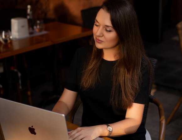 Eine junge Frau sitzt vor einem Laptop und arbeitet.