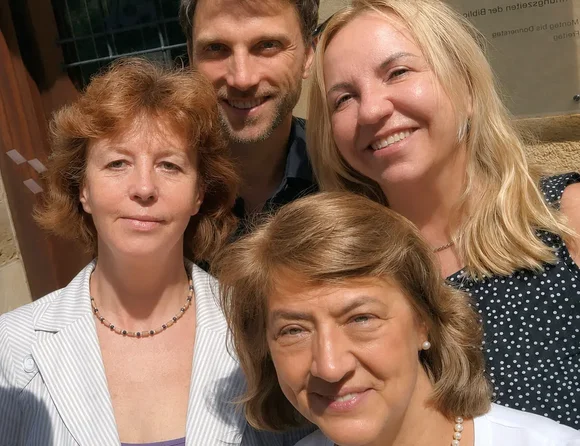 Ein Foto von drei Frauen und einem Mann vor einer Hausfassade.