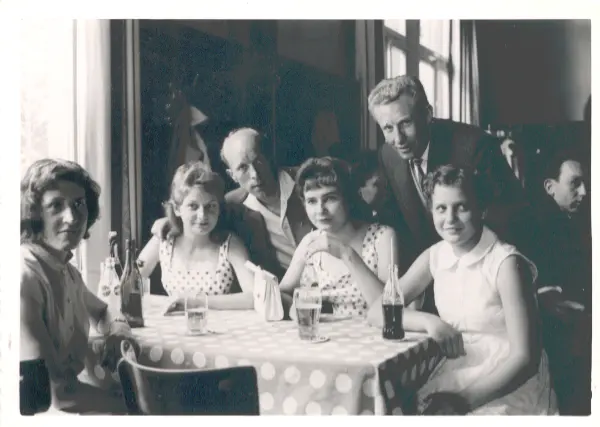 Zwei Männer und vier Frauen sitzen gemeinsam an einem Tisch in einer Wirtschaft. Auf dem Tisch stehen verschiedene Getränke.