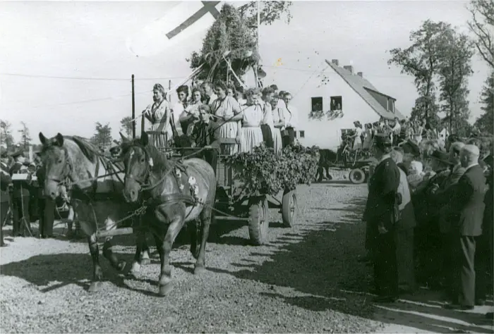 Auf einem geschmückten Wagen, gezogen von zwei Pferden, stehen viele Frauen um die Erntekrone.