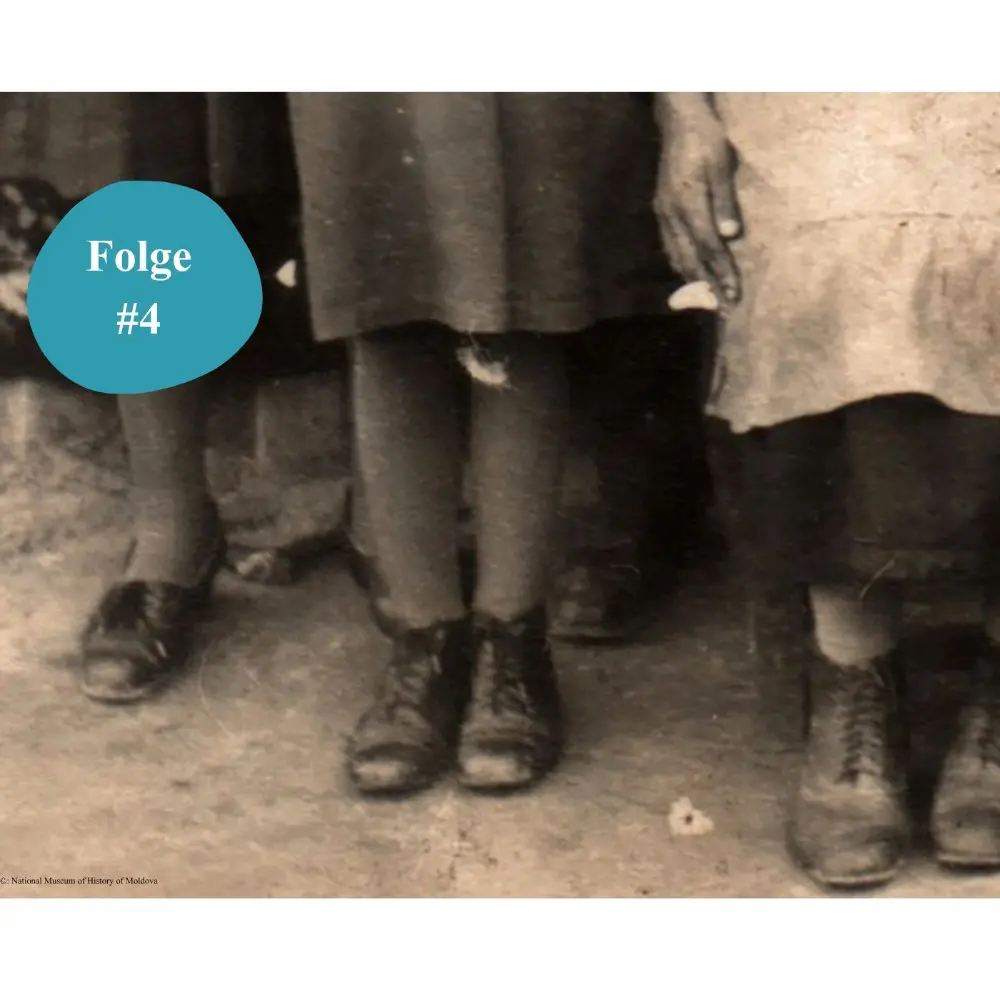 Ausschnitt aus einer historischen Fotografie mit einem Detail der Füße dreier Mädchen in dicken Strümpfen und schwarzen Schuhen.