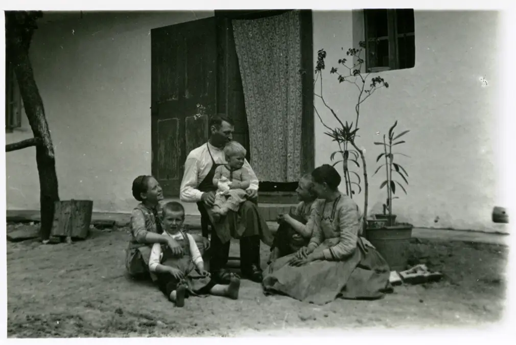 Familie sitzt vor dem Haus und genießt gemeinsame Zeit.