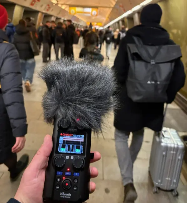 Hand mit Aufnahmegerät in der Prager U-Bahn.