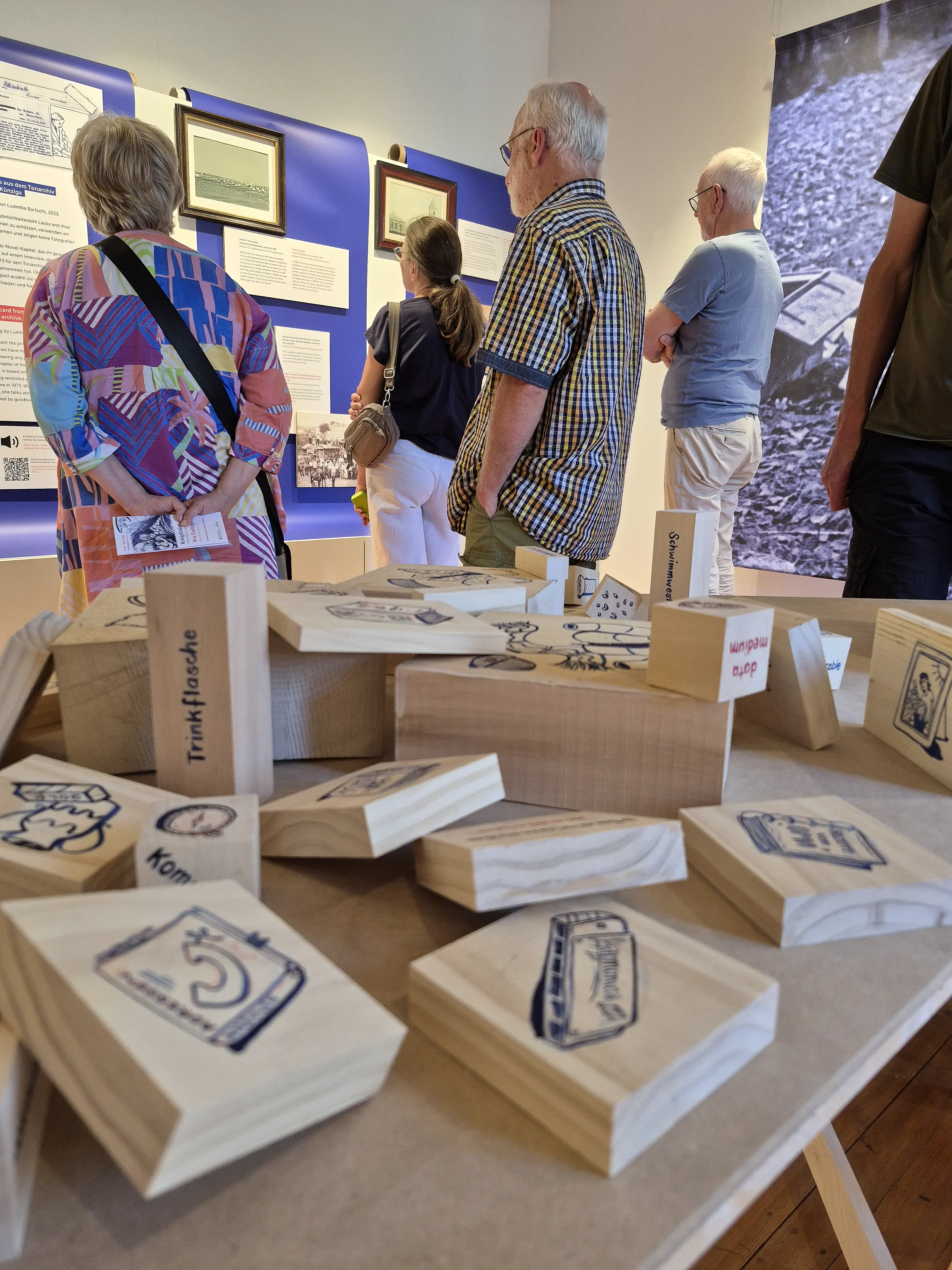 Menschen in einem Ausstellungsraum betrachten Exponate.