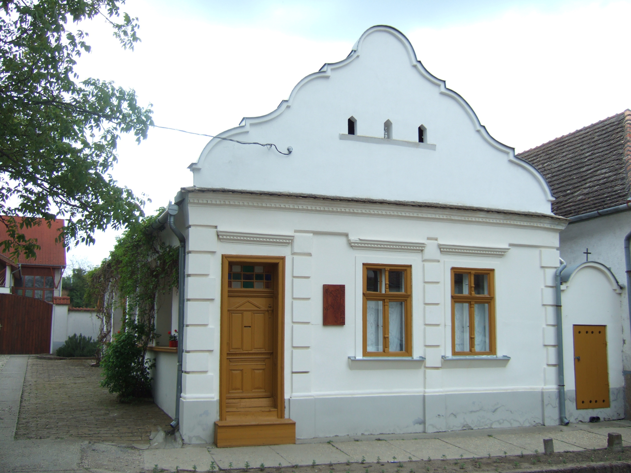 Die Giebelseite eines einstöckigen Hauses mit weißer Fassade.