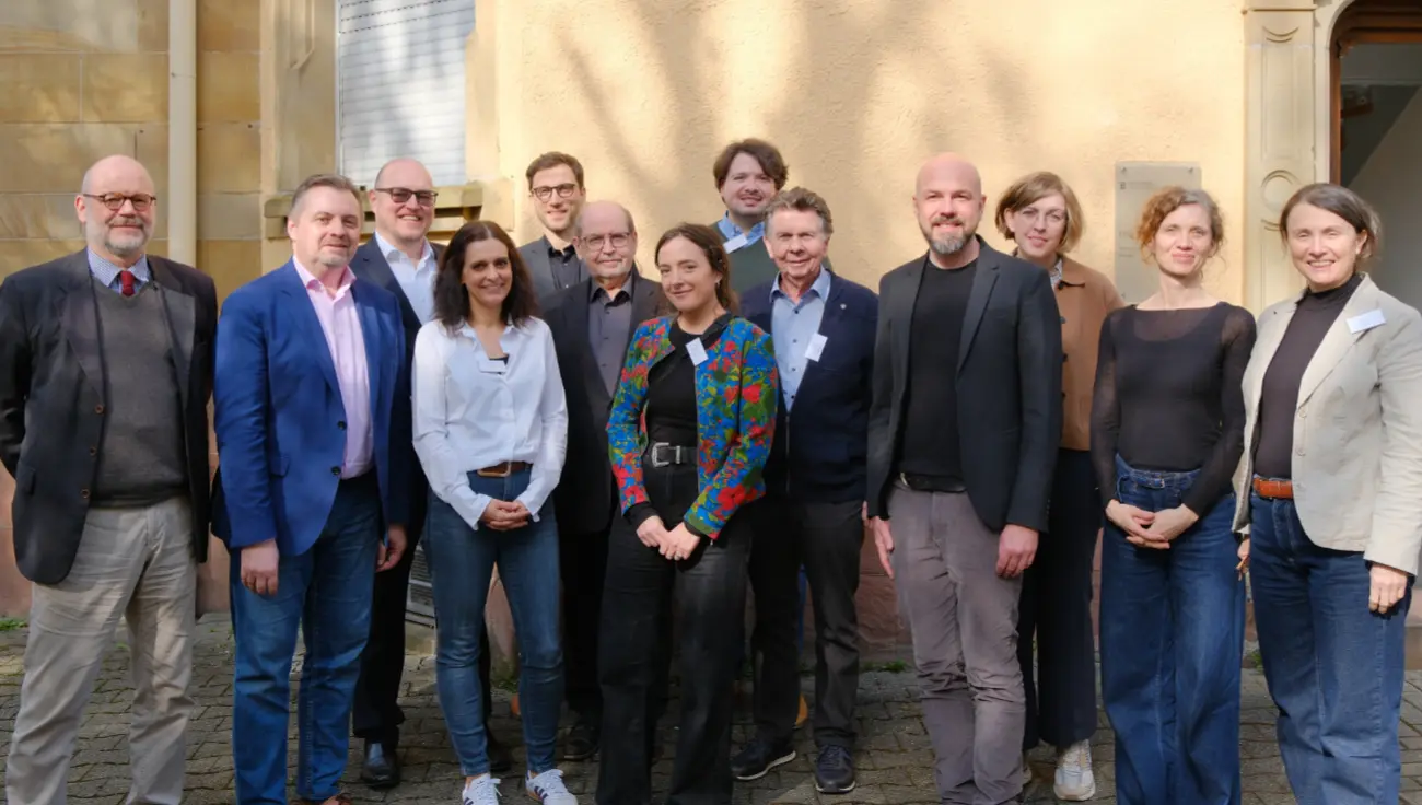 Gruppenfoto von Männern und Frauen vor einer Hausfassade 