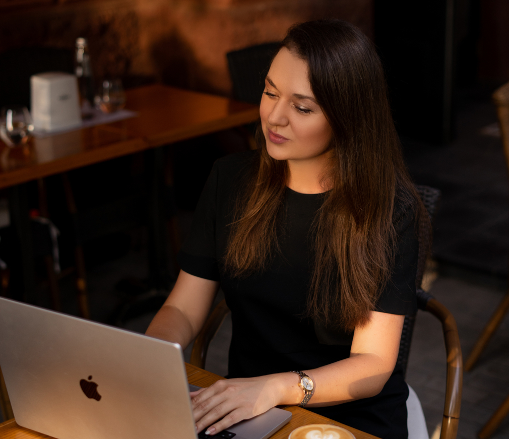 Eine junge Frau sitzt vor einem Laptop und arbeitet.