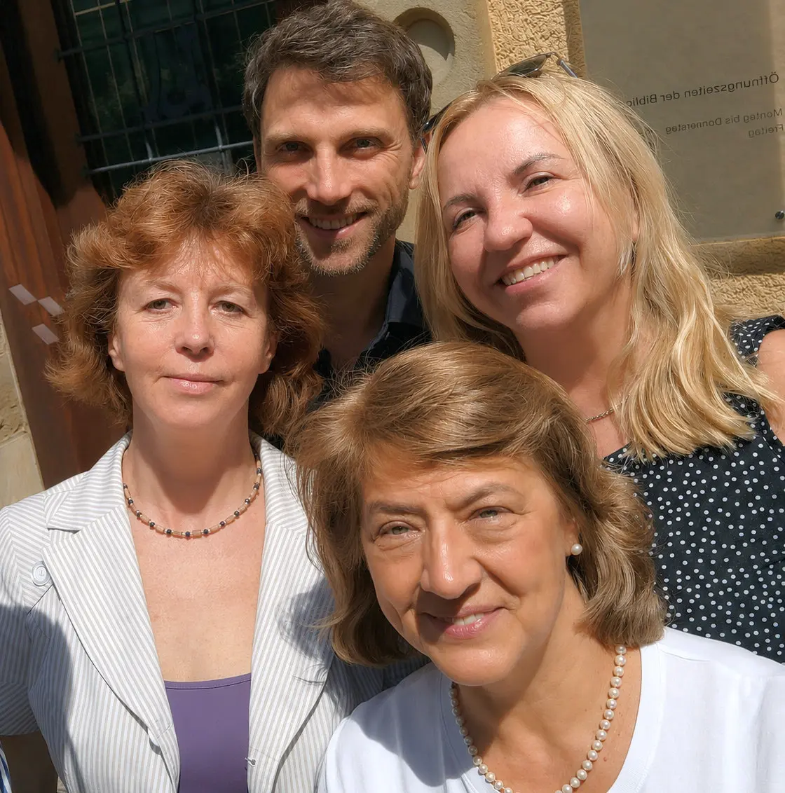 Ein Foto von drei Frauen und einem Mann vor einer Hausfassade.