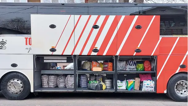 Ein Reisebus mit offenem Kofferraum in dem sich viele bunte Taschen befinden