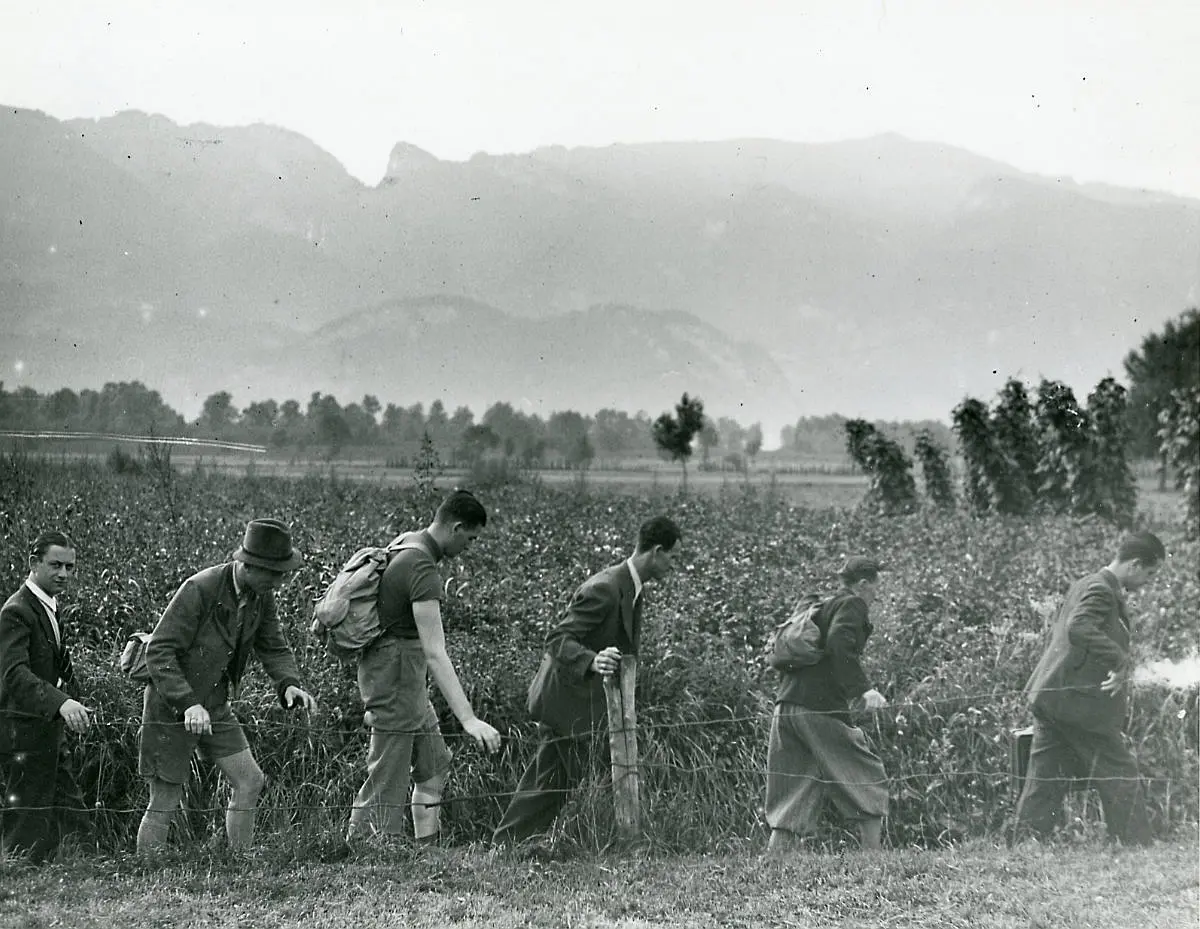 Sechs Männer laufen in einer Reihe an einem Feld entlang