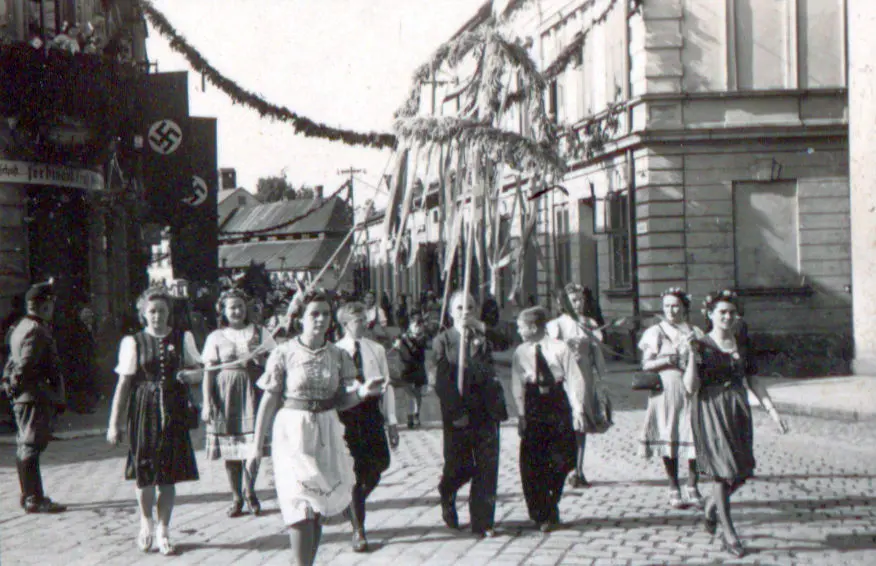 Ein Festumzug auf einer Straße. Menschen in Trachten tragen eine Erntedankfestkrone.
